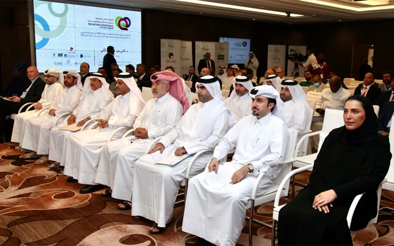 Wide view of the ESG Qatar 2025 conference hall - rows of attendees, sponsor banners and a TV cameraman filming.